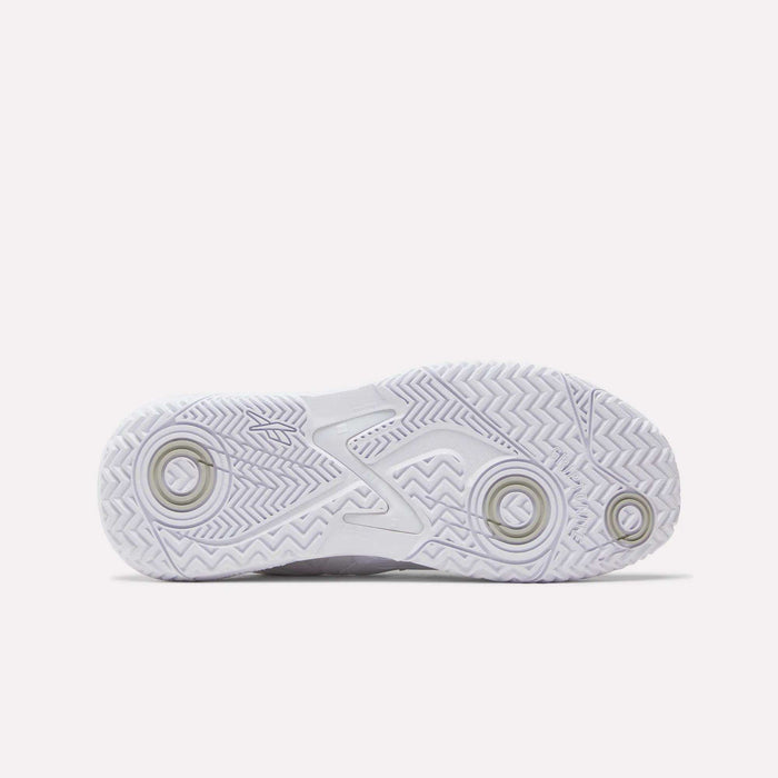 The image displays the outsole of Reebok Women's Phase Evo Tennis Shoes, a white athletic shoe featuring a textured zigzag tread and circular grip patterns for enhanced traction—perfect for durable tennis performance.