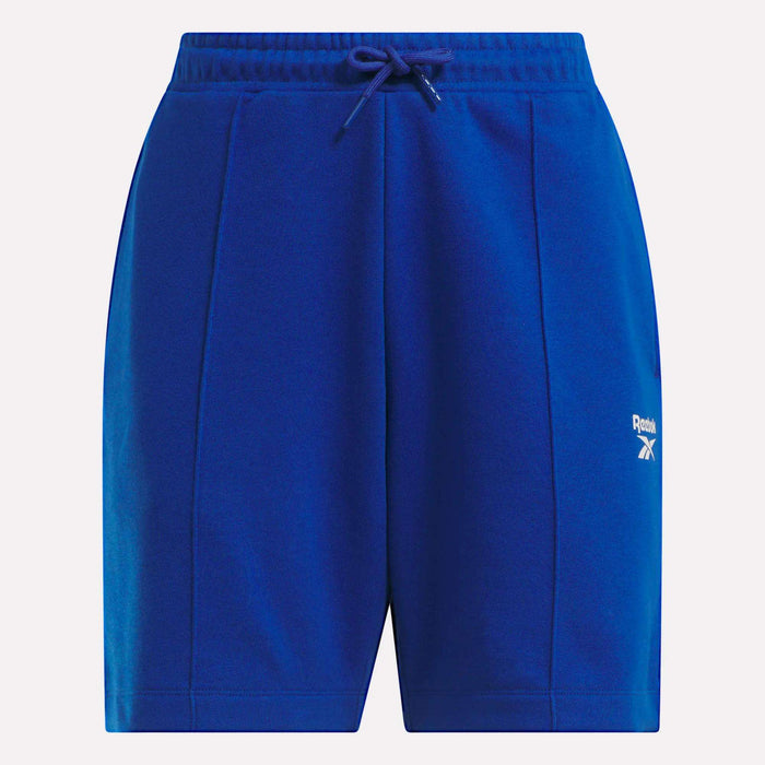 Reebok Women's Pintuck Long Shorts in bright blue feature soft cotton-blend fleece, an elastic waistband with drawstring, side pockets, and a white logo on the left thigh.