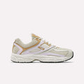 The Reebok Women's Premier Trinity Shoes feature beige, tan, and white mesh panels, white laces, and a cushioned sole for a retro tech look—shown from the side on a plain light background.