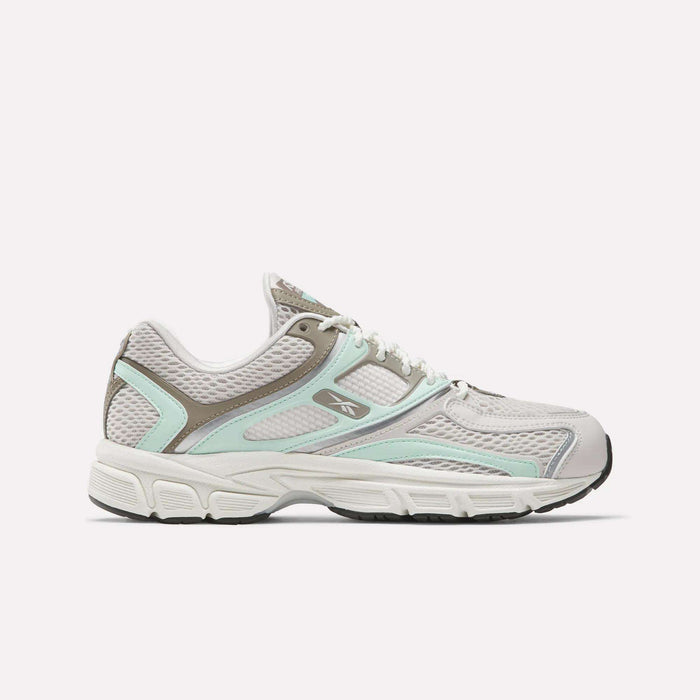 The Reebok Women's Premier Trinity Shoes are shown in a side profile, featuring gray and white colors with light aqua and taupe accents, mesh panels, and a black sole, blending retro tech style with modern design against a plain background.