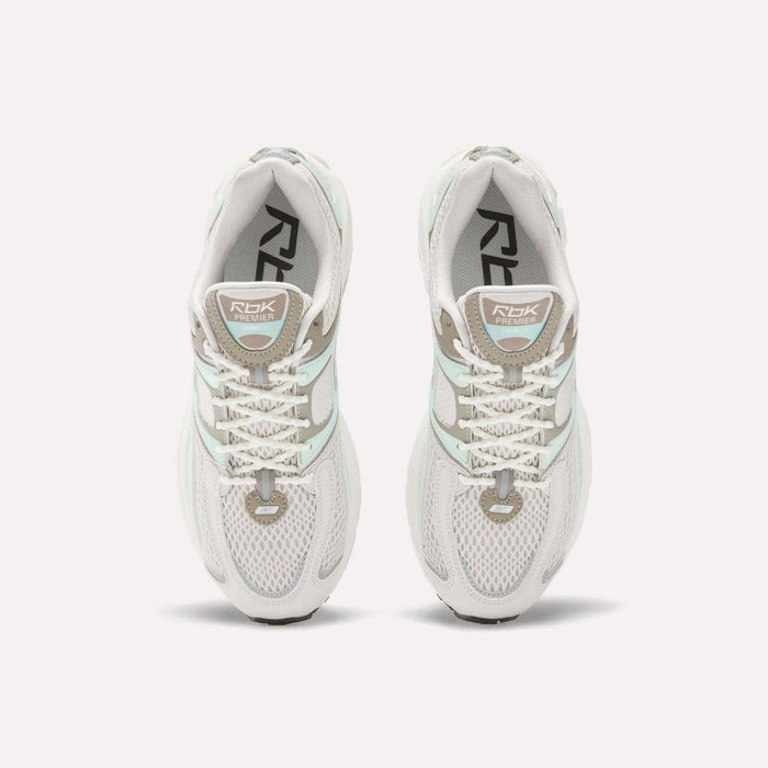 Top view of Reebok Women's Premier Trinity Shoes in white with gray and light green accents, mesh panels, and RBK branding—highlighting retro tech style on a clean white background.