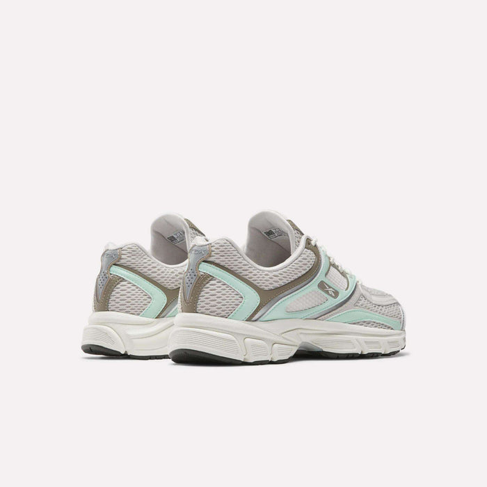 The Reebok Women's Premier Trinity Shoes, inspired by retro tech, feature grey mesh with mint green and beige accents, white midsoles, and black outsoles. Displayed from the rear angle against a plain white background.