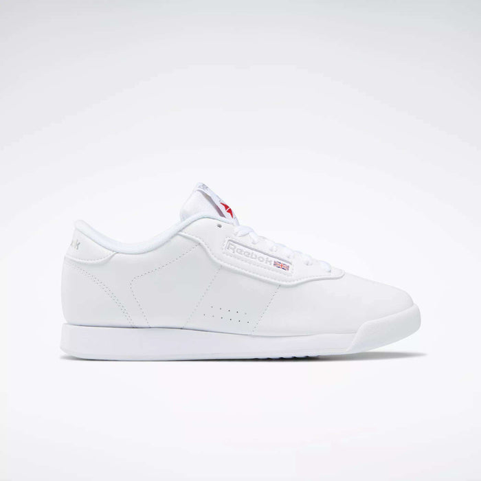 The Reebok Women's Princess Shoes feature a classic white design with a flat sole, cushioned comfort, and subtle branding on the side and tongue—a timeless choice displayed on a plain light background.