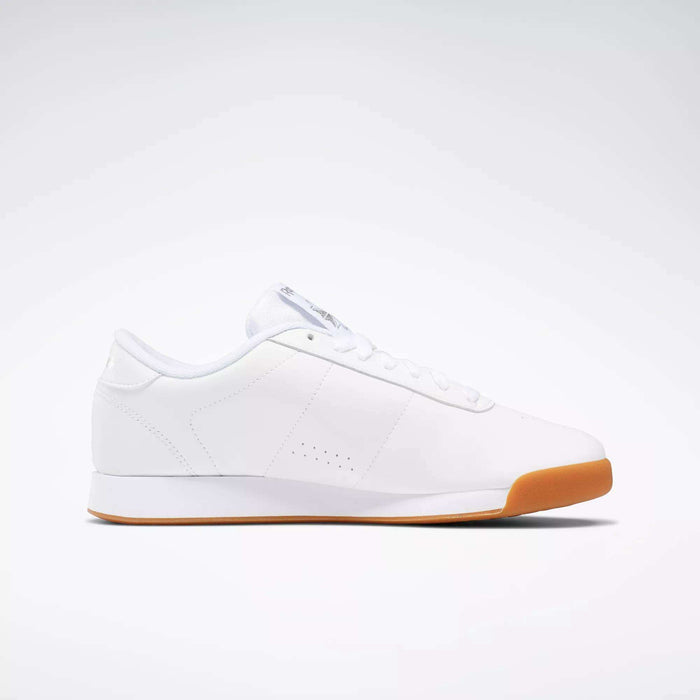 The Women's Princess Shoes by Reebok are classic white low-top sneakers with a minimal design, white laces, subtle stitching, and a cushioned light brown rubber sole, shown in profile against a plain light background.