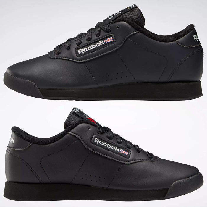 A pair of black Reebok Women's Princess Shoes with cushioned soles, black laces, and the Reebok logo with a British flag on the tongue and side. The heritage style is displayed from both outer and inner views on a plain background.