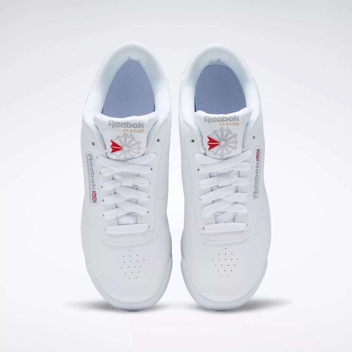A pair of white Reebok Women's Princess Shoes viewed from above, featuring perforated toes, white laces, and classic Reebok branding with a red and gray logo—a timeless heritage style women’s sneaker.