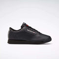 A pair of black Reebok Women's Princess Wide Shoes featuring a low-cut lace-up design, cushioned sole, and subtle Union Jack detail is shown against a plain light gray background.