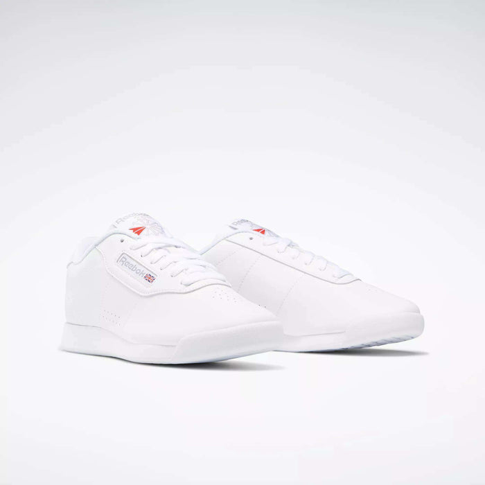 The Women's Princess Wide Shoes by Reebok feature a classic, minimalistic design with the iconic Union Jack logo and branding on the side, showcased against a plain white background.