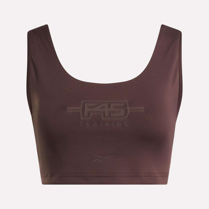 Introducing the Women's Reebok x F45 Training Sports Bra. This brown sports bra by Reebok features "F45 Training" embossed on the front, with a subtle Reebok logo beneath. Designed with a scoop neckline and wide shoulder straps, it stands out against a plain background to keep the focus on the garment.