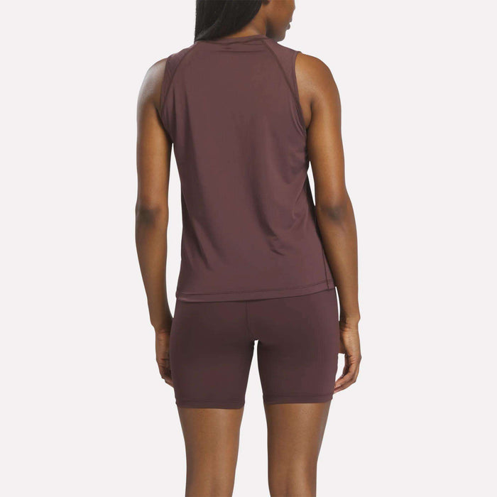 A woman stands facing away, wearing a sleeveless maroon Women's Reebok x F45 Training Tank Top. The background is plain and light-colored.