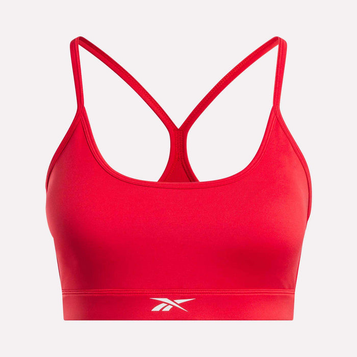The Reebok Women's Strappy Sports Bra is shown against a plain white background, featuring a vibrant red color, thin racerback straps, and a small white Reebok logo on the lower front band. Designed for medium-impact workouts, it is crafted from quick-drying fabric for optimal comfort and performance.