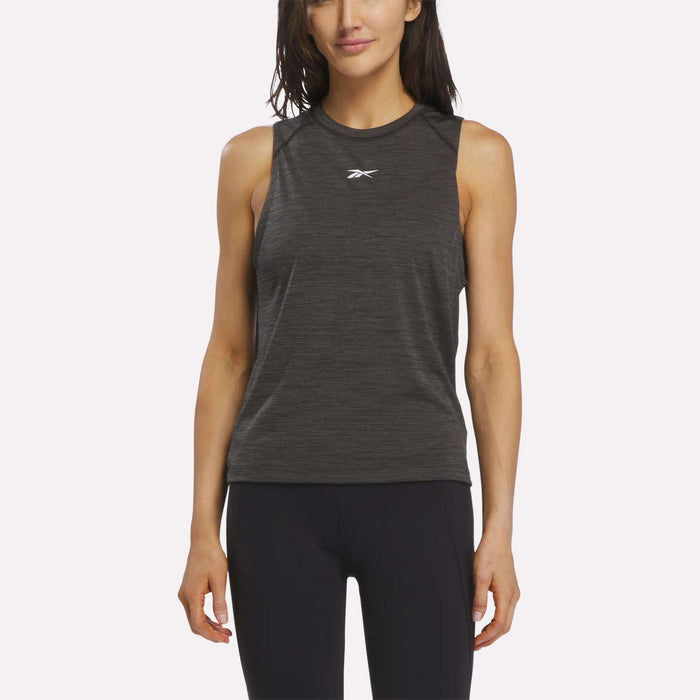 A woman wearing a sleeveless Women's Training Tank Top by Reebok in Black Melange, featuring RBK-DRY technology and a subtle Reebok logo on the chest, paired with black leggings and standing against a plain white background.