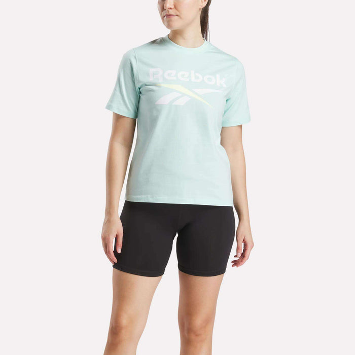 A woman wearing the Reebok Women's Two-Color Logo Crew Short Sleeve Tee in green.