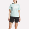 A woman wearing the Reebok Women's Two-Color Logo Crew Short Sleeve Tee in green.