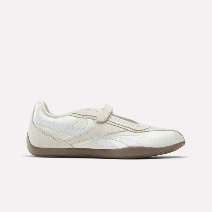 The Reebok Women's Ultra Lo Mary Jane Shoes are cream and white athletic shoes with a gum sole, velcro strap, and sleek low-profile design, inspired by classic Reebok styles.