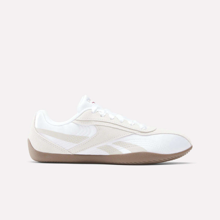 The Reebok Women's Ultra Lo Shoes feature a white athletic design with beige accents, a gum rubber sole, and lace-up closure—blending sporty style with a sleek, low-profile silhouette. Shown in side view on a light background.