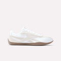 The Reebok Women's Ultra Lo Shoes feature a white athletic design with beige accents, a gum rubber sole, and lace-up closure—blending sporty style with a sleek, low-profile silhouette. Shown in side view on a light background.