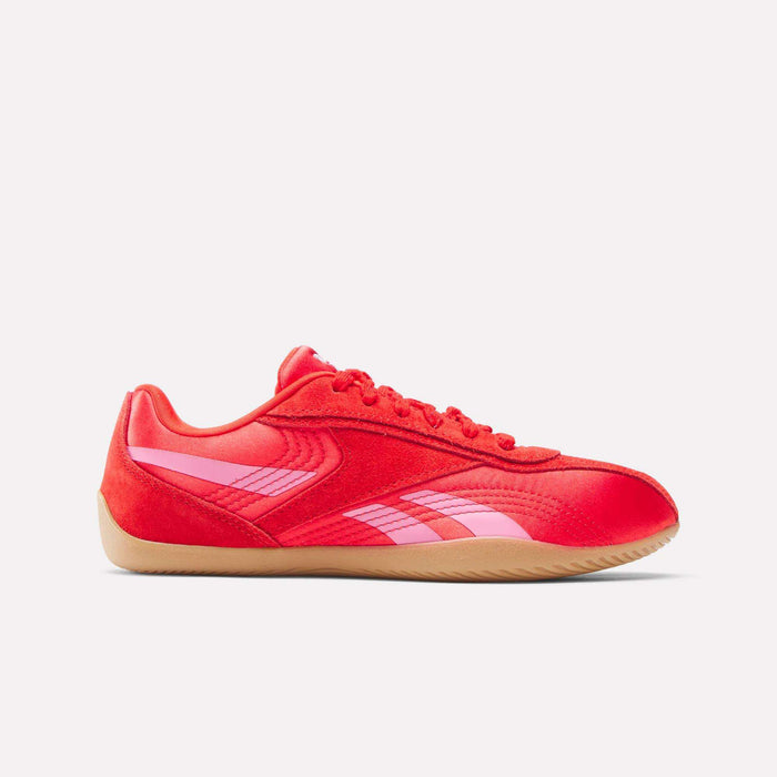 The Reebok Women's Ultra Lo Shoes feature a bright red athletic design with pink logo accents, red laces, and a light tan rubber sole, showcasing a sporty look against a plain white background.