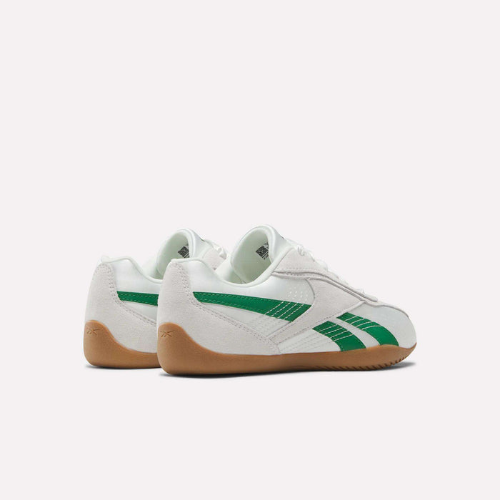 A pair of white Reebok Women's Ultra Lo Shoes with green stripes and brown gum soles are positioned side by side, angled away, on a plain light background.