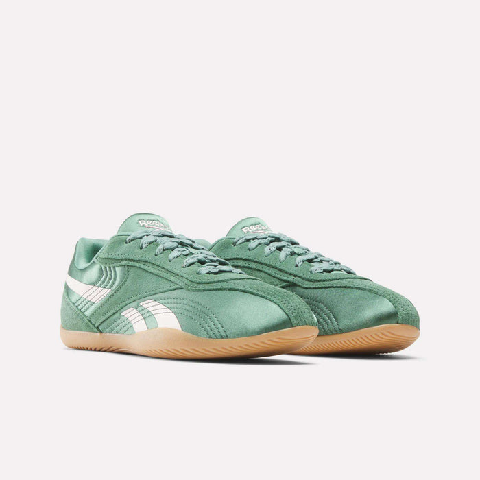 The Reebok Women's Ultra Lo Shoes feature a green design with white side stripes, light brown rubber soles, and a low-profile, stylish, and lightweight build, shown on a plain white background.