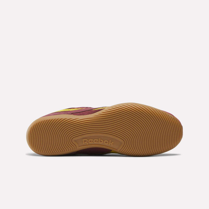 The Reebok Women's Ultra Lo Shoes are shown from the bottom, featuring a maroon upper and a textured light brown rubber sole with the Reebok logo in the center. This low-profile design ensures lightweight, all-day comfort.