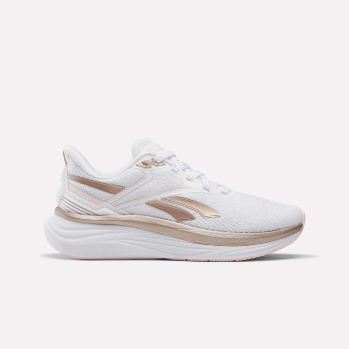 The Reebok Women's Viva Speed Shoes feature a white design with metallic rose gold accents and a thick, cushioned sole, displayed in a side profile against a plain white background.