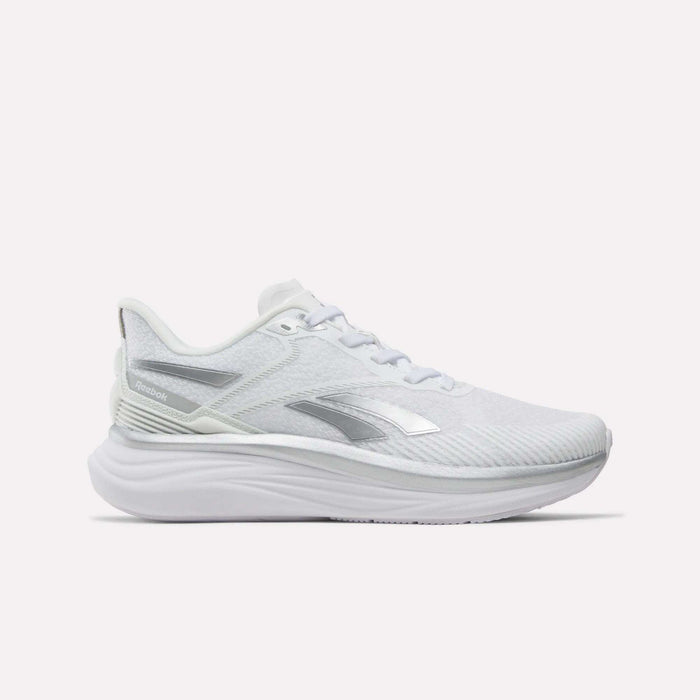 Introducing the Reebok Women’s Viva Speed Shoes—featuring a sleek white design with silver accents, a breathable mesh upper, and a thick cushioned sole for superior comfort and support. Photographed from the side against a plain white background, these athletic running shoes are an ideal choice for anyone seeking both style and performance.