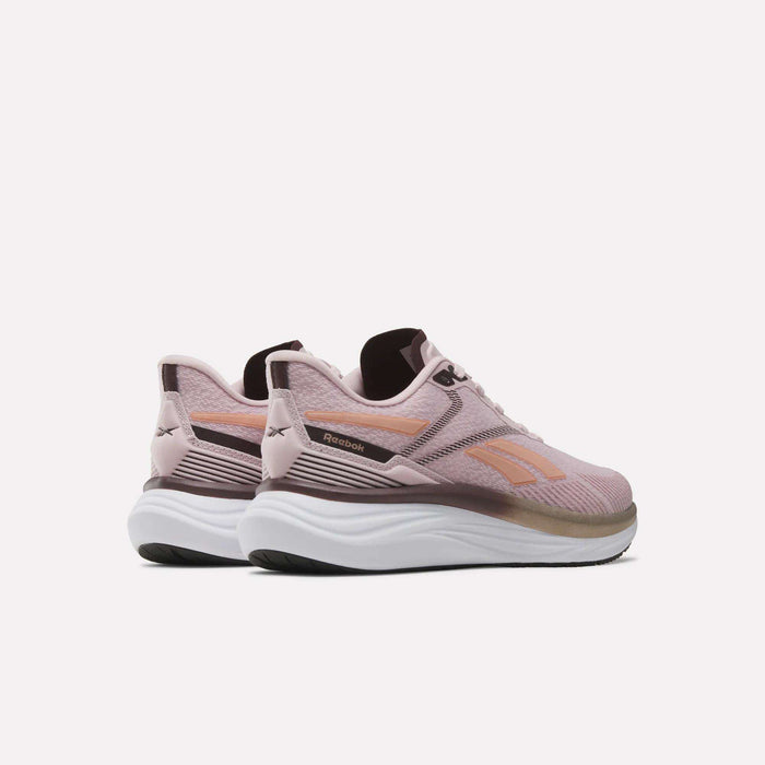 A pair of Reebok Women’s Viva Speed Shoes in pink and white is displayed against a plain white background, angled to highlight the side and back details. These cushioned running shoes offer a breathable design for comfort and support during everyday activities.