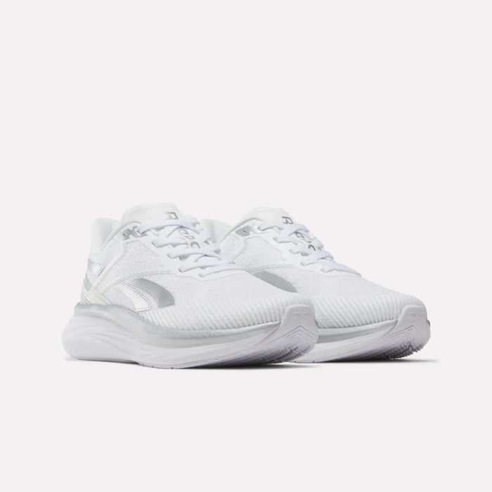 A pair of Reebok Women’s Viva Speed Shoes in white with silver accents, featuring breathable mesh uppers and chunky cushioned soles, displayed against a plain white background.