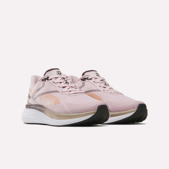 A pair of Women's Viva Speed Shoes by Reebok in light pink, featuring white midsoles, black outsoles, and peach accents. These breathable and cushioned running shoes are displayed against a plain white background.