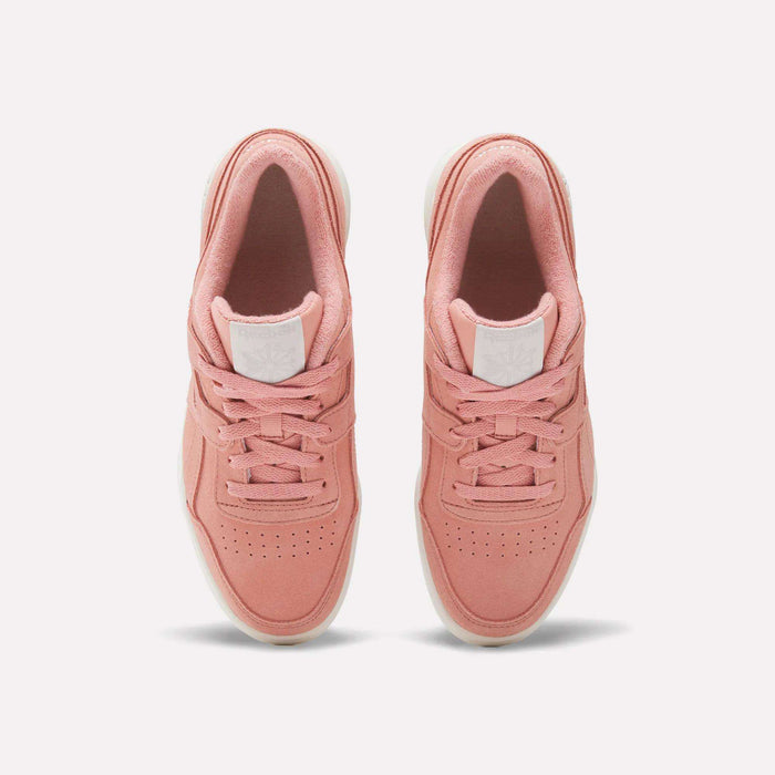 A pair of Women's Workout Plus Shoes by Reebok in pink with white soles, top view highlighting laces, perforated toes, and a white logo patch on the tongue—ideal for capturing vintage 80s workout style.