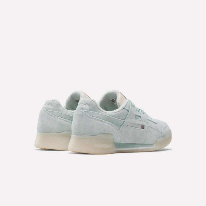 A pair of Women's Workout Plus Shoes by Reebok in light mint green suede with off-white soles, inspired by classic 80s fitness style, are displayed on a white background facing away and slightly to the side.
