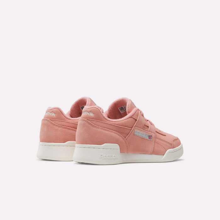 The Reebok Women's Workout Plus Shoes in pink, shown from the back and side with white soles, showcase a classic 80s fitness style against a plain white background.