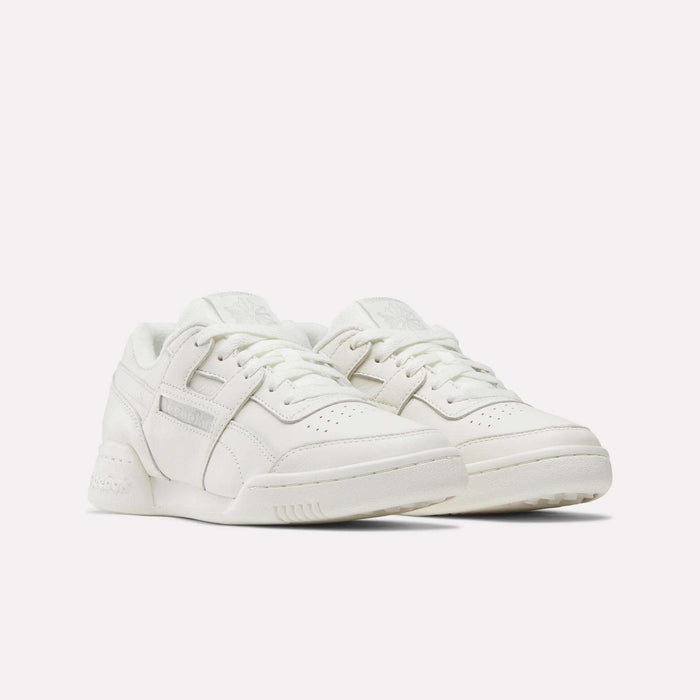 A pair of Women's Workout Plus Shoes by Reebok, featuring a white low-top design with laces, perforated toe boxes, and subtle stitching details, displayed against a plain white background.