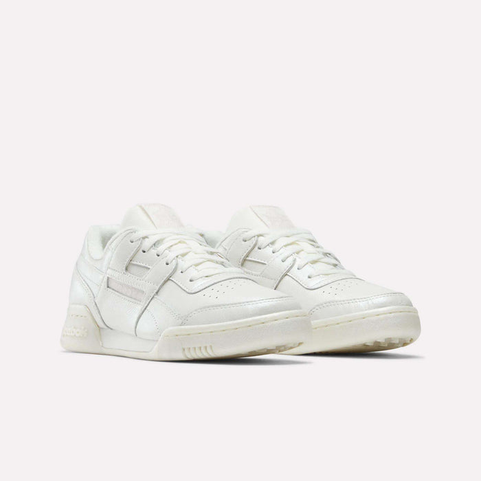 The Women's Workout Plus Shoes by Reebok feature an off-white low-top design, lace-up fronts, perforated toes, and subtle side branding, bringing classic 80s fitness style to women's sneakers. Shown on a plain white background.
