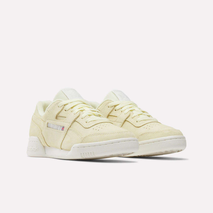 A pair of Women's Workout Plus Shoes by Reebok in pale yellow with white soles, lace-up fronts, and subtle side branding capture classic '80s fitness style, shown on a plain white background.