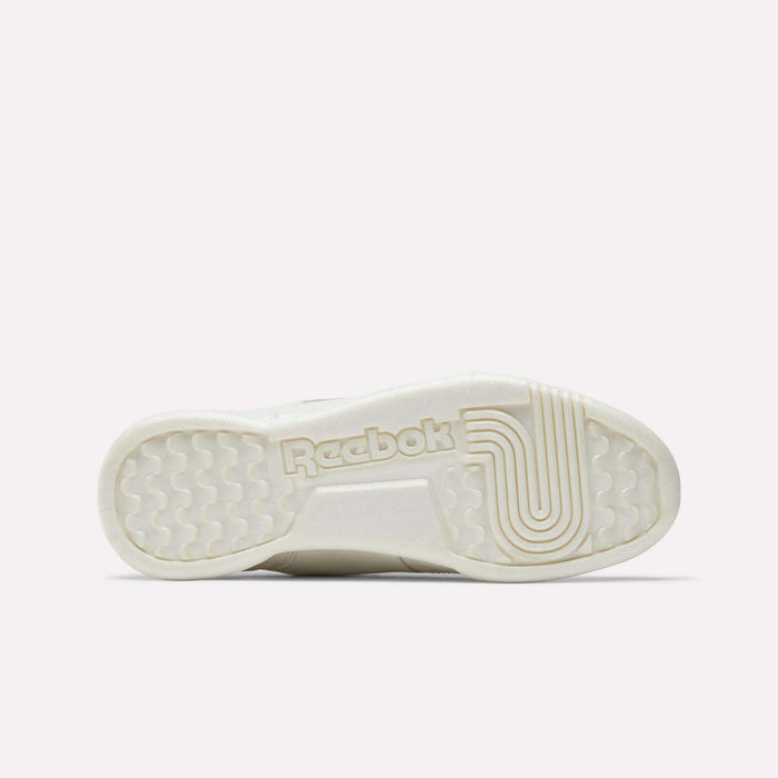 The image displays the white rubber sole of Reebok Women's Workout Plus Shoes, highlighted by the Reebok logo and textured grip patterns—a tribute to classic 80s fitness style in women’s sneakers.