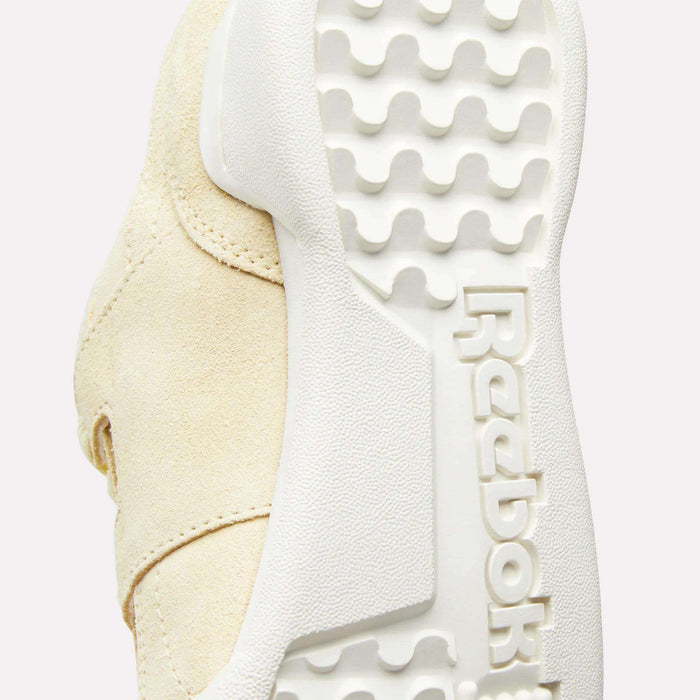 Close-up of the sole of the Women's Workout Plus Shoes by Reebok, highlighting the textured white rubber outsole with an embossed Reebok logo and a wavy tread pattern inspired by '80s fitness style.