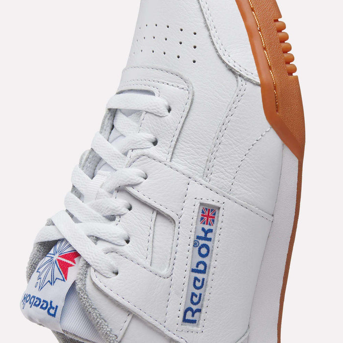 Close-up of Reebok Women's Workout Plus Shoes in white with brown gum sole, showcasing the Reebok logo, Union Jack flag, and stitched leather details—an iconic women's sneaker inspired by classic '80s fitness style.
