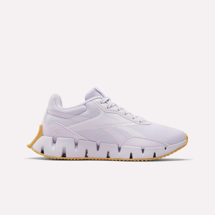 The Reebok Women's Zig Dynamica STR Shoes are light purple athletic sneakers with a breathable mesh upper, jagged EVA-cushioned midsole, and light brown rubber outsole, shown in side profile on a plain white background.