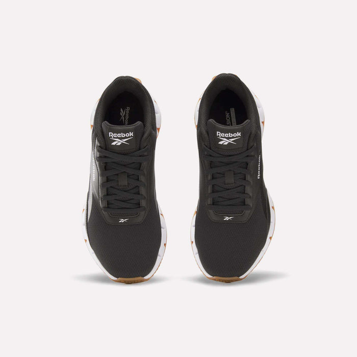 A pair of Reebok Women's Zig Dynamica STR Shoes in black with white soles, featuring a responsive midsole and the Reebok logo on the tongue, shown from above on a plain light background.
