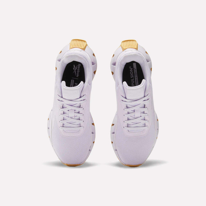 The Reebok Women's Zig Dynamica STR Shoes are white athletic sneakers with breathable mesh uppers and tan accents on the heels and soles, shown from above against a plain light background.