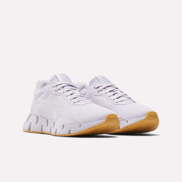 A pair of Reebok Women's Zig Dynamica STR Shoes in white, featuring breathable mesh uppers, chunky EVA midsoles, and tan rubber outsoles, displayed side by side on a plain white background.