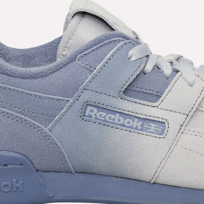 Close-up of light blue and gray Reebok Workout Plus OG Shoes, highlighting the classic silhouette with suede texture, stitched detailing, and the Reebok logo with Union Jack on the side. The retro shoes feature matching laces and a slightly raised midsole.