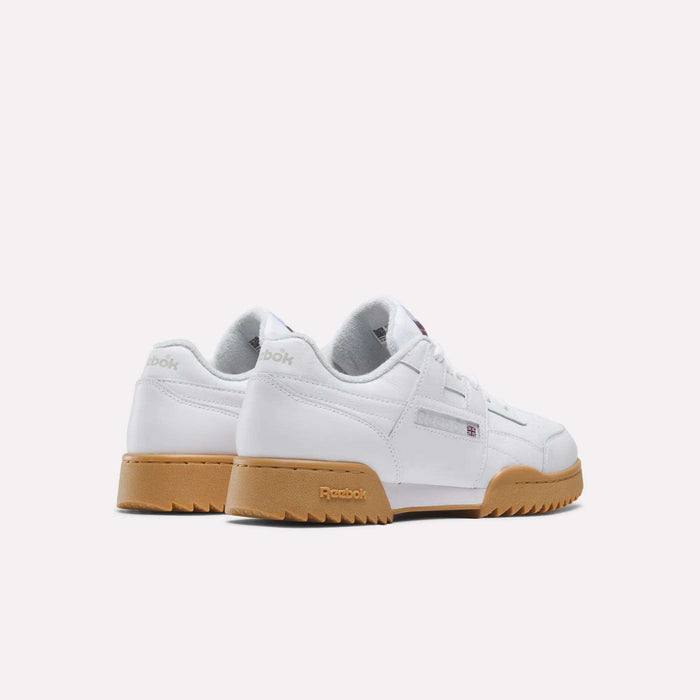 A pair of Reebok Workout Plus Ripple Shoes in white leather with light brown gum soles, shown from the back and angled left. Featuring a low-cut design, Reebok branding, and a subtle vintage vibe.