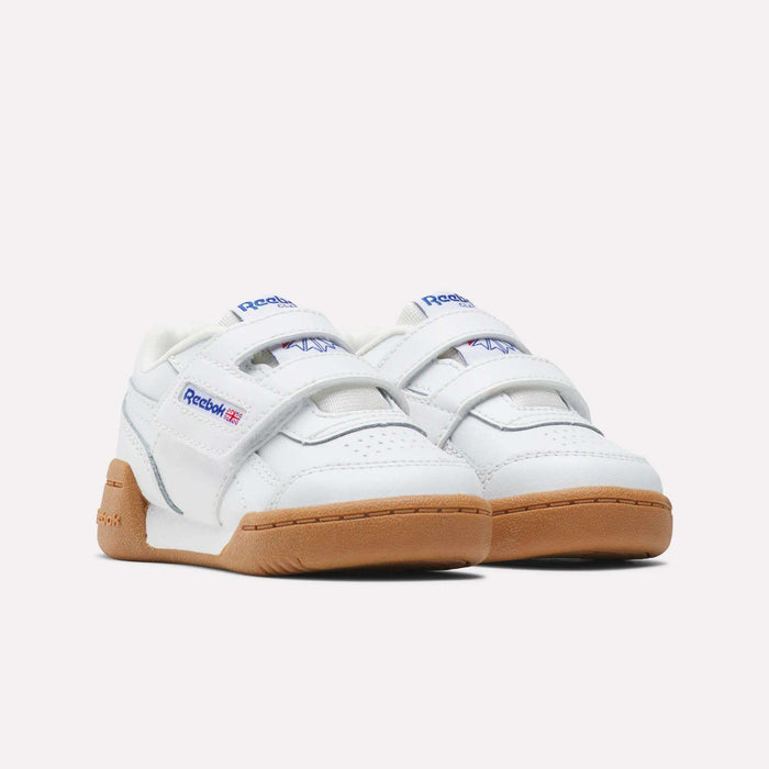 The Reebok Kids' Workout Plus Shoes for babies and toddlers feature white uppers, Velcro straps, light brown rubber soles, and display the Reebok logo with a small Union Jack on the side.