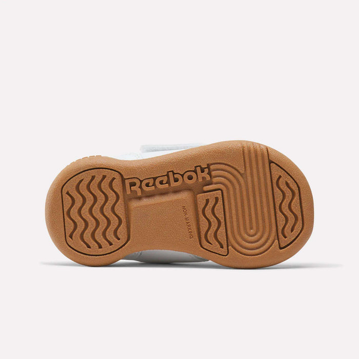 The image shows the sole of Reebok Kids' Workout Plus Shoes for babies and toddlers, with a brown rubber outsole, wavy and circular tread patterns, Reebok branding, and "NON-MARKING" embossed near the center.