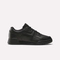 The Reebok Workout Plus Shoes - Big Kids feature a black low-top design with lace-up closure and classic Reebok branding, bringing retro style to juniors’ footwear, shown against a plain white background.