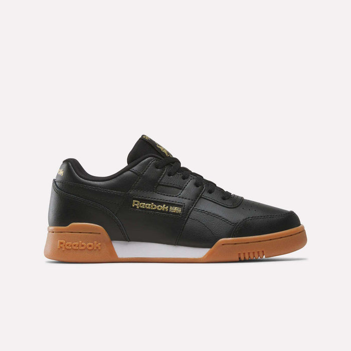 The Reebok Workout Plus Shoes for big kids feature a black design with gold logo accents, black laces, and a brown gum sole. Shown in side profile on a white background—perfect sporty shoes for any junior collection.