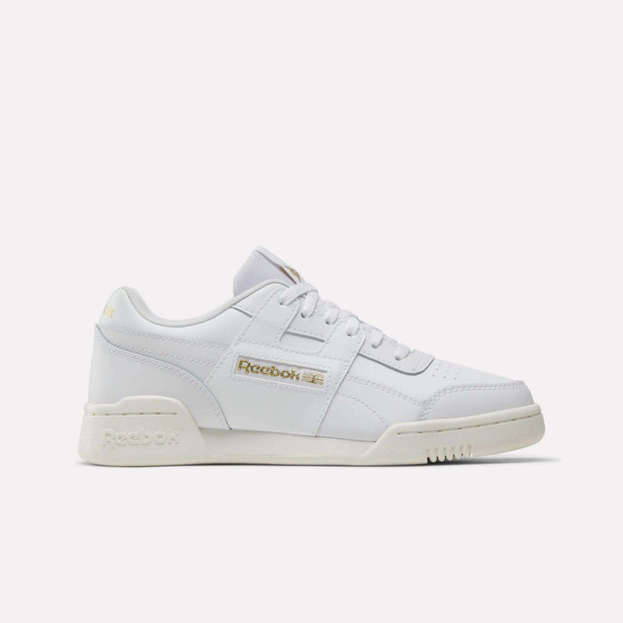 The Reebok Workout Plus Shoes - Big Kids are white low-top sneakers with gold branding on the side and heel, white laces, and an off-white sole—ideal sporty footwear for juniors, shown on a plain white background.
